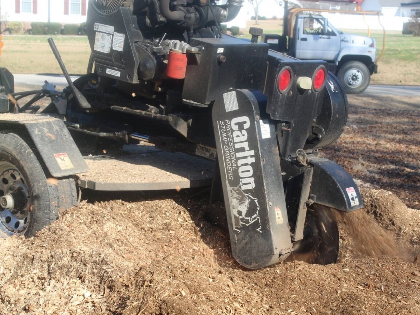 Caterpillar trenching machine with a vertical auger digging through soil in a muddy outdoor work site