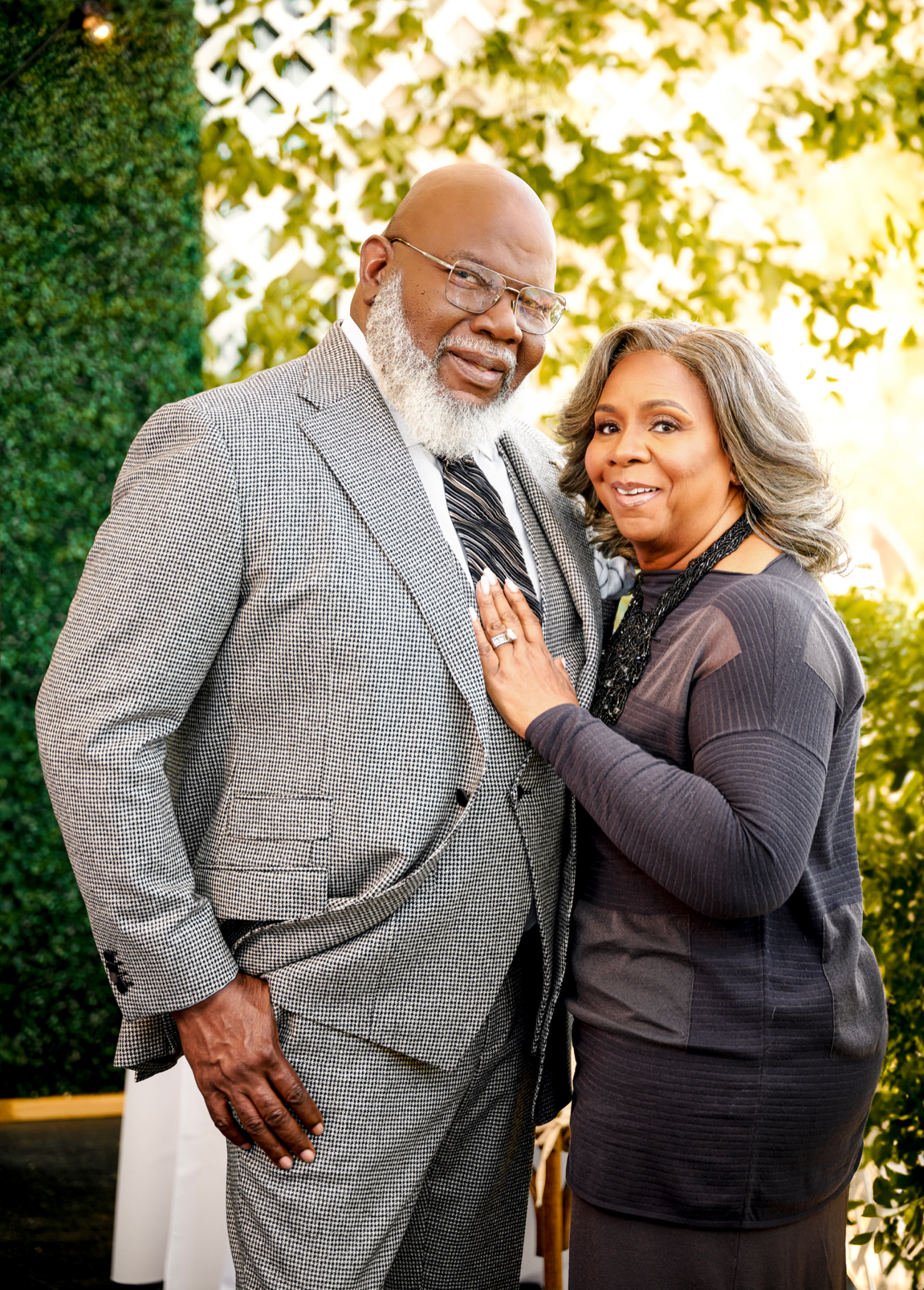 A man in a suit and tie is standing next to a woman in a black shirt.