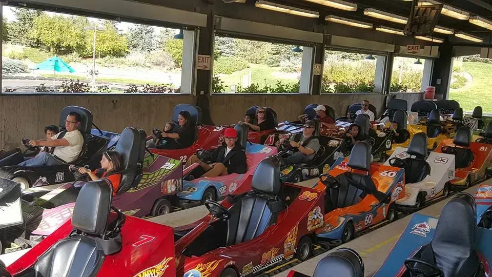 A group of people are riding go karts at an amusement park.