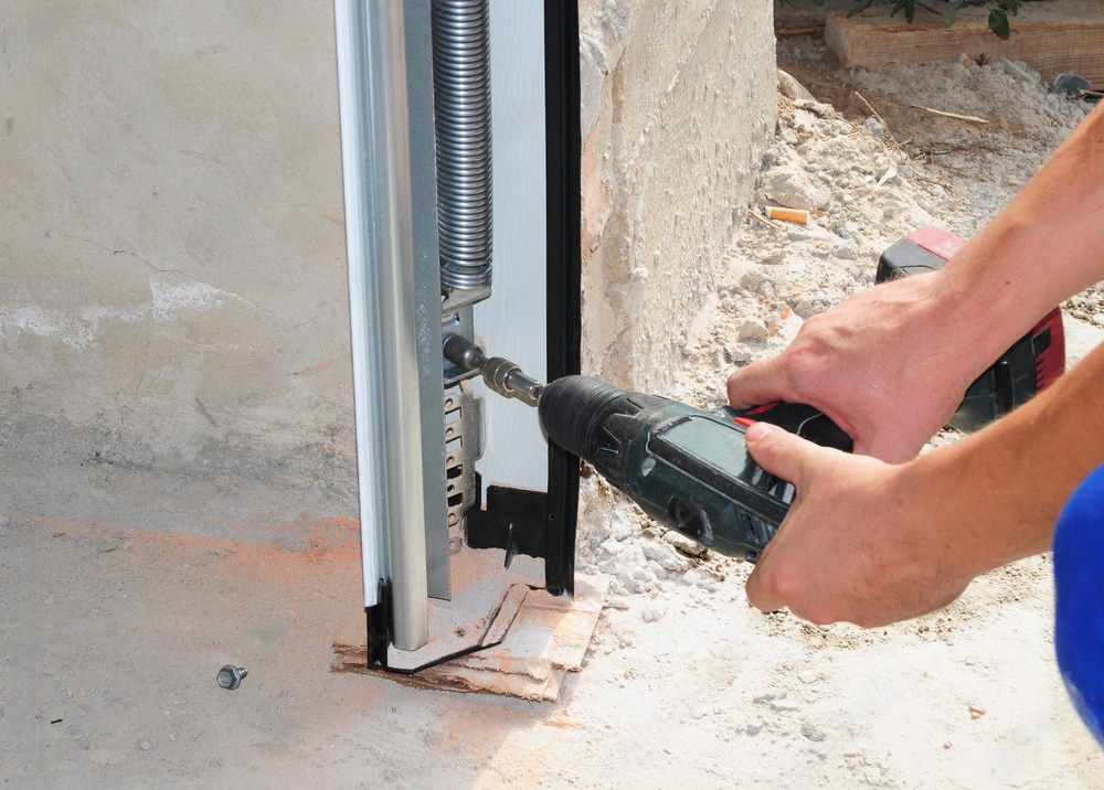a person is using a drill to fix a garage door .