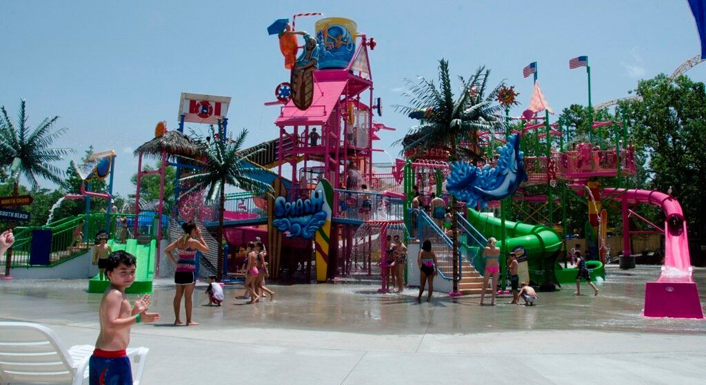 Colorful outdoor water park with playful slides, fountains, and children on a wet splash pad