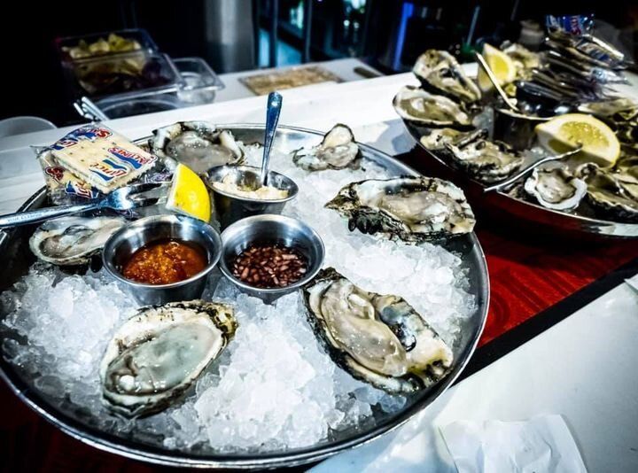 Oysters on ice with lemon wedges and dipping sauces on a seafood platter
