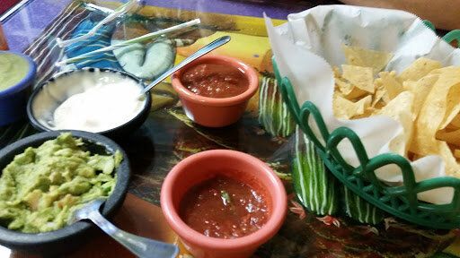 Mexican appetizers with guacamole, salsa, sour cream, and tortilla chips on a table