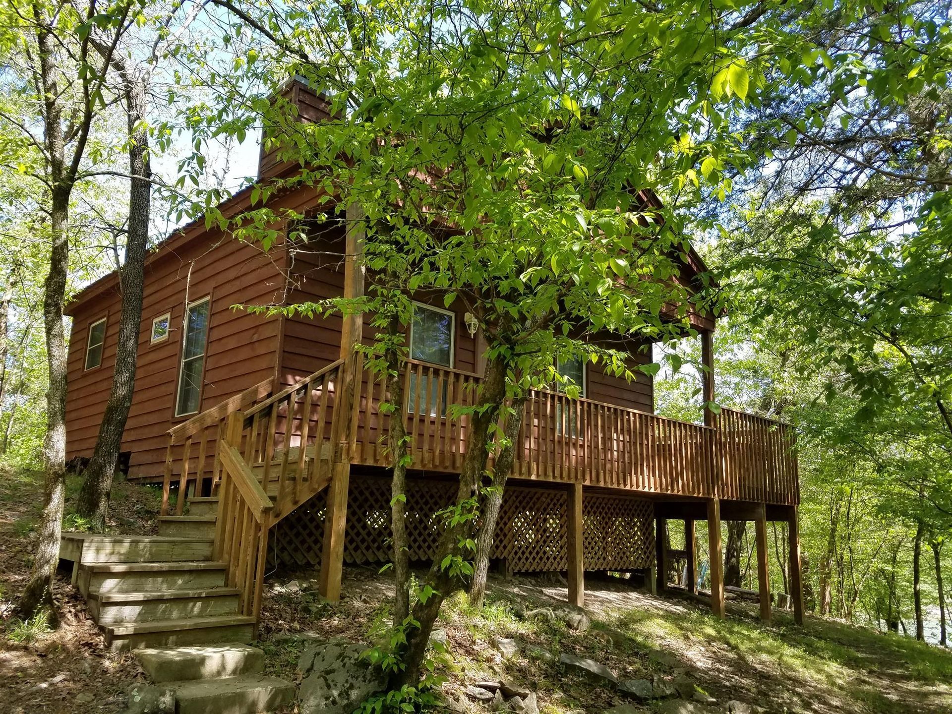 Wooden cabin with porch and steps in a leafy forest setting