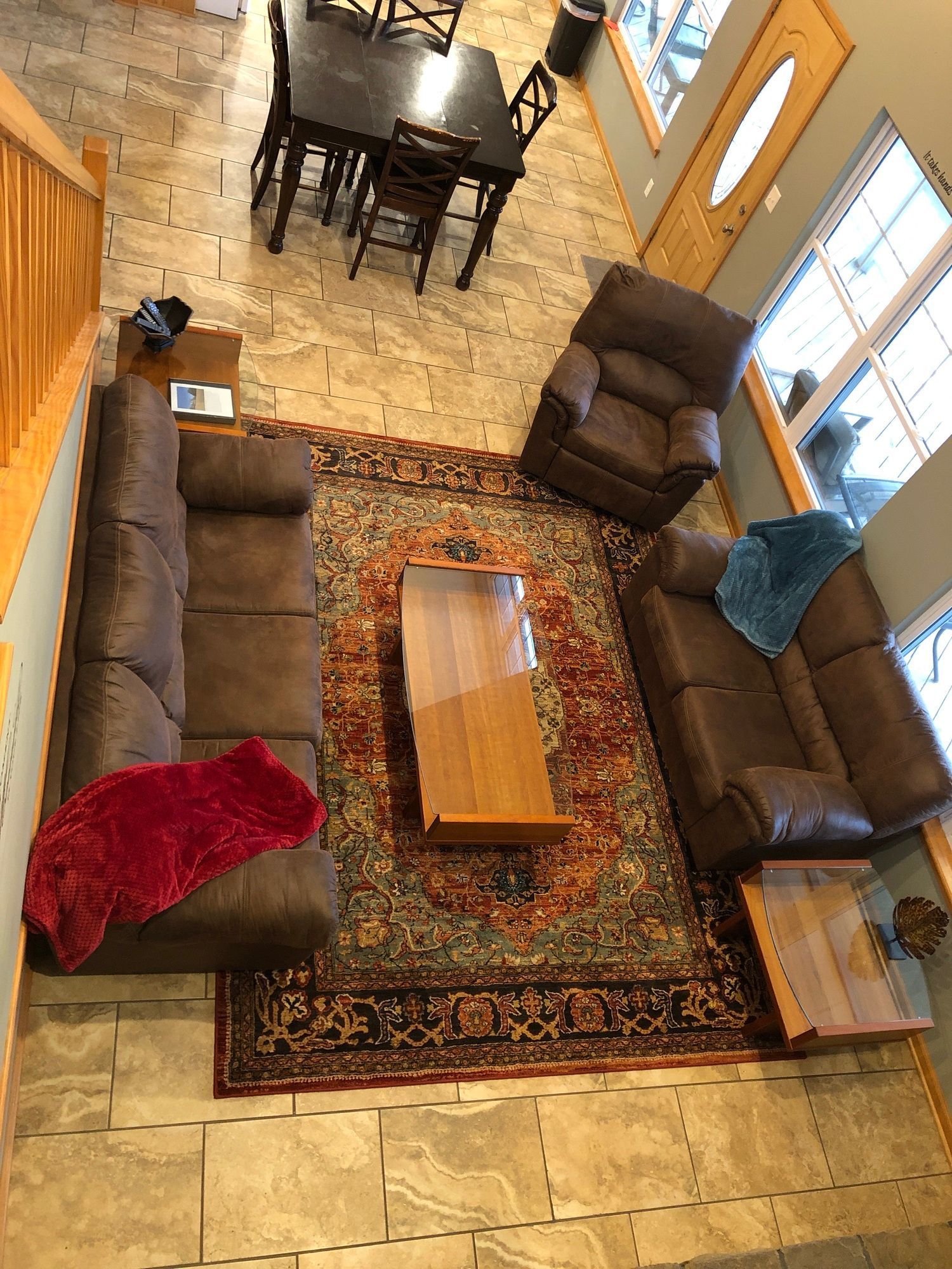 Overhead view of a living room with sectional sofas, armchair, coffee table, and patterned rug on tile floor