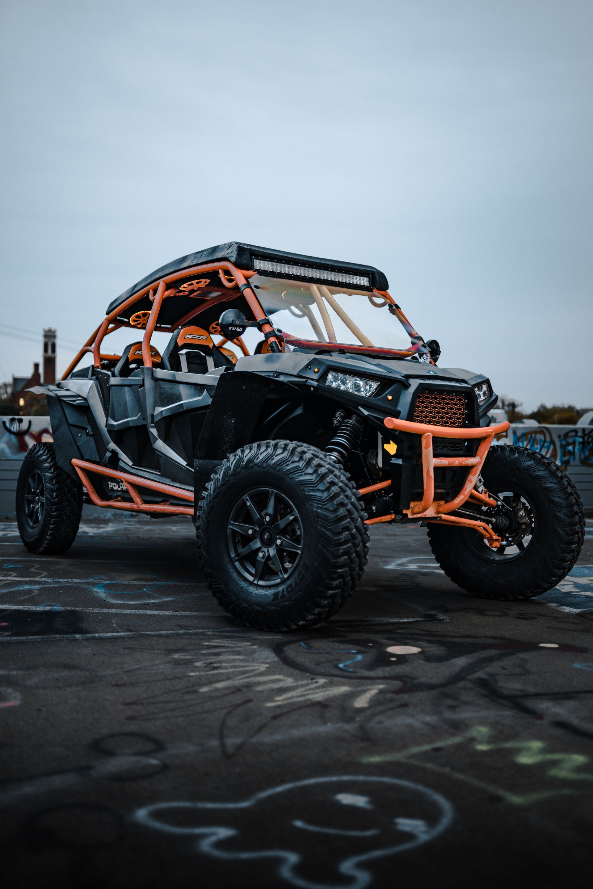Orange-and-black off-road buggy on a wet pavement under an overcast sky