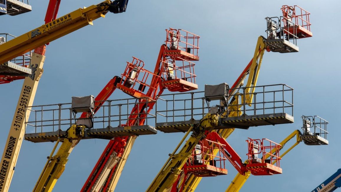 Varias plataformas elevadoras rojas y amarillas se alzaban contra un cielo azul despejado.