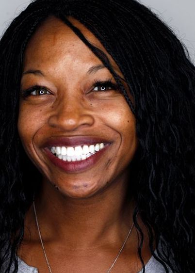Smiling person with dark hair against a plain gray background