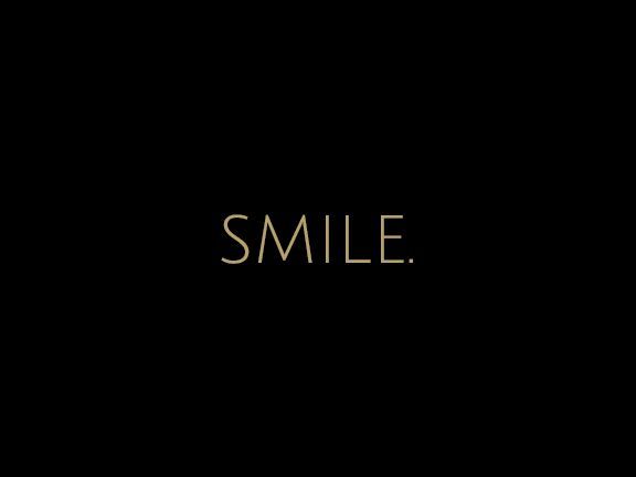 Black background with the word “SMILE.” in thin gold letters centered.