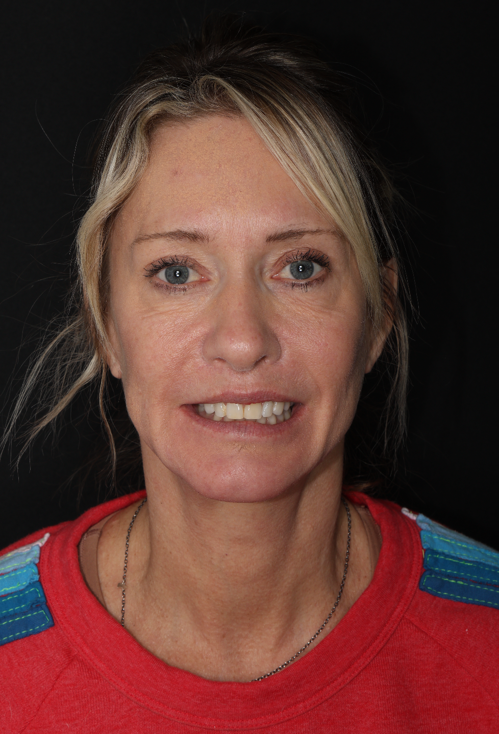 Portrait of a smiling person in a red sweater against a dark background