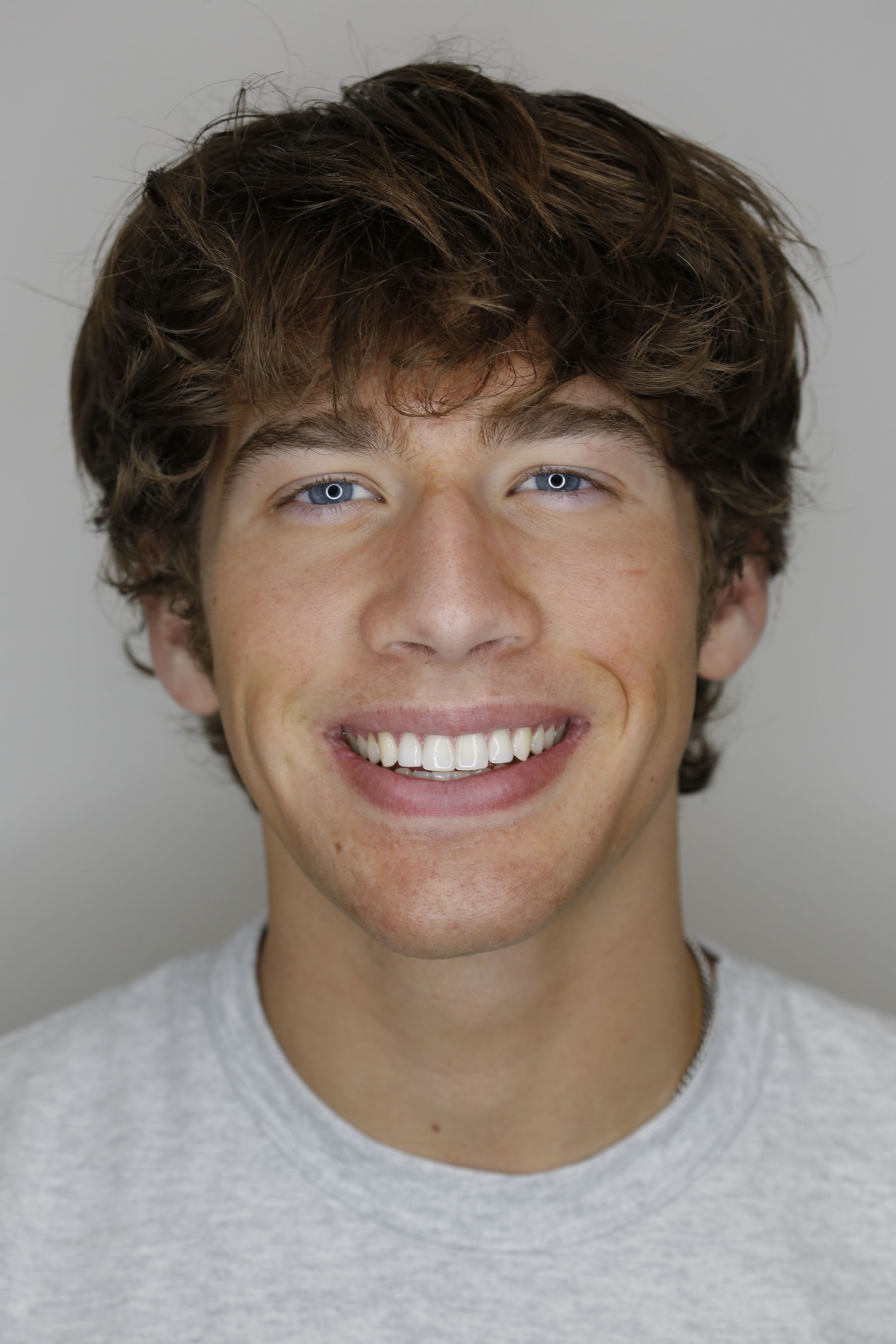 A young man with curly hair is smiling for the camera.
