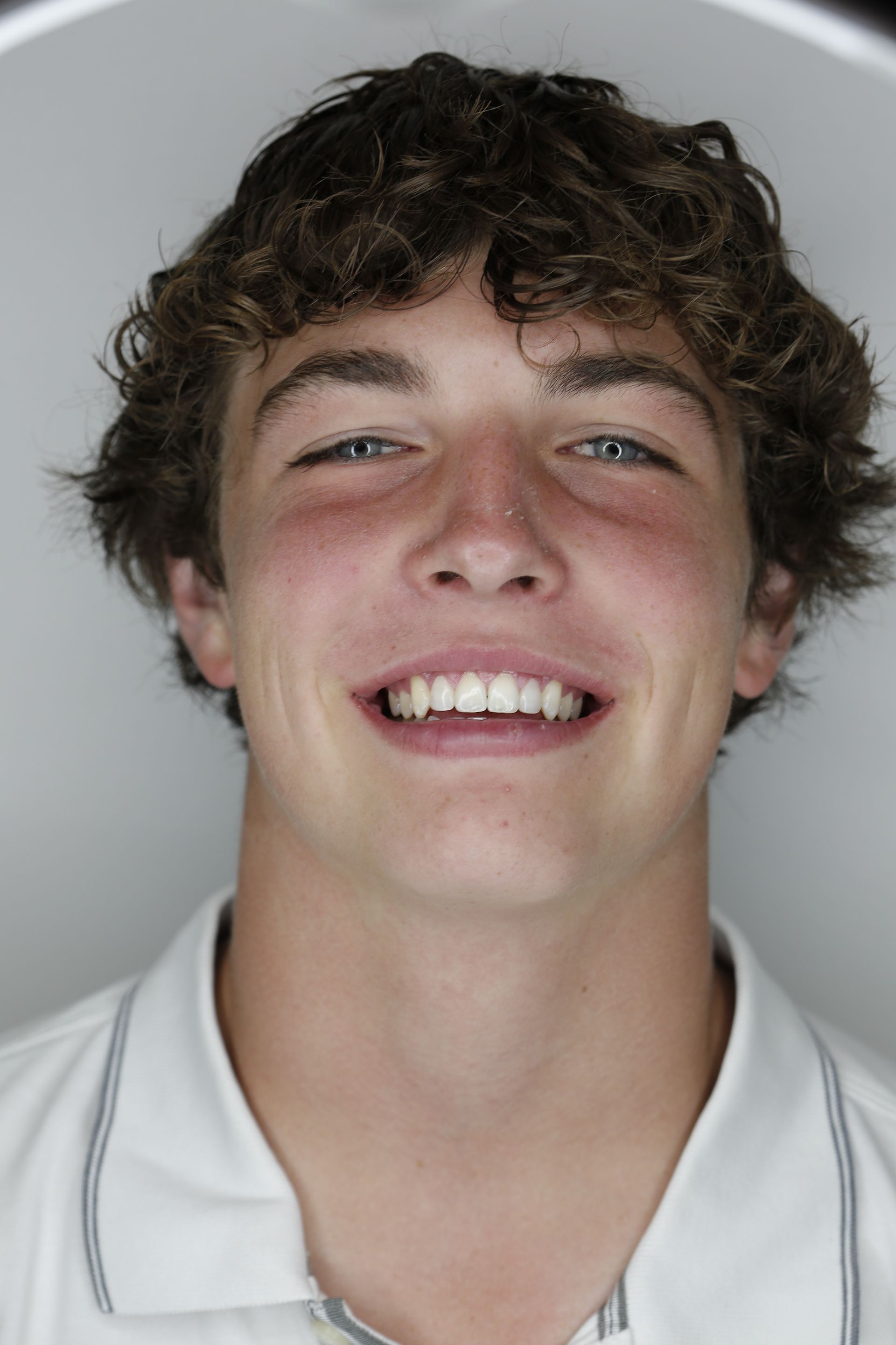 A young man with curly hair is smiling for the camera.