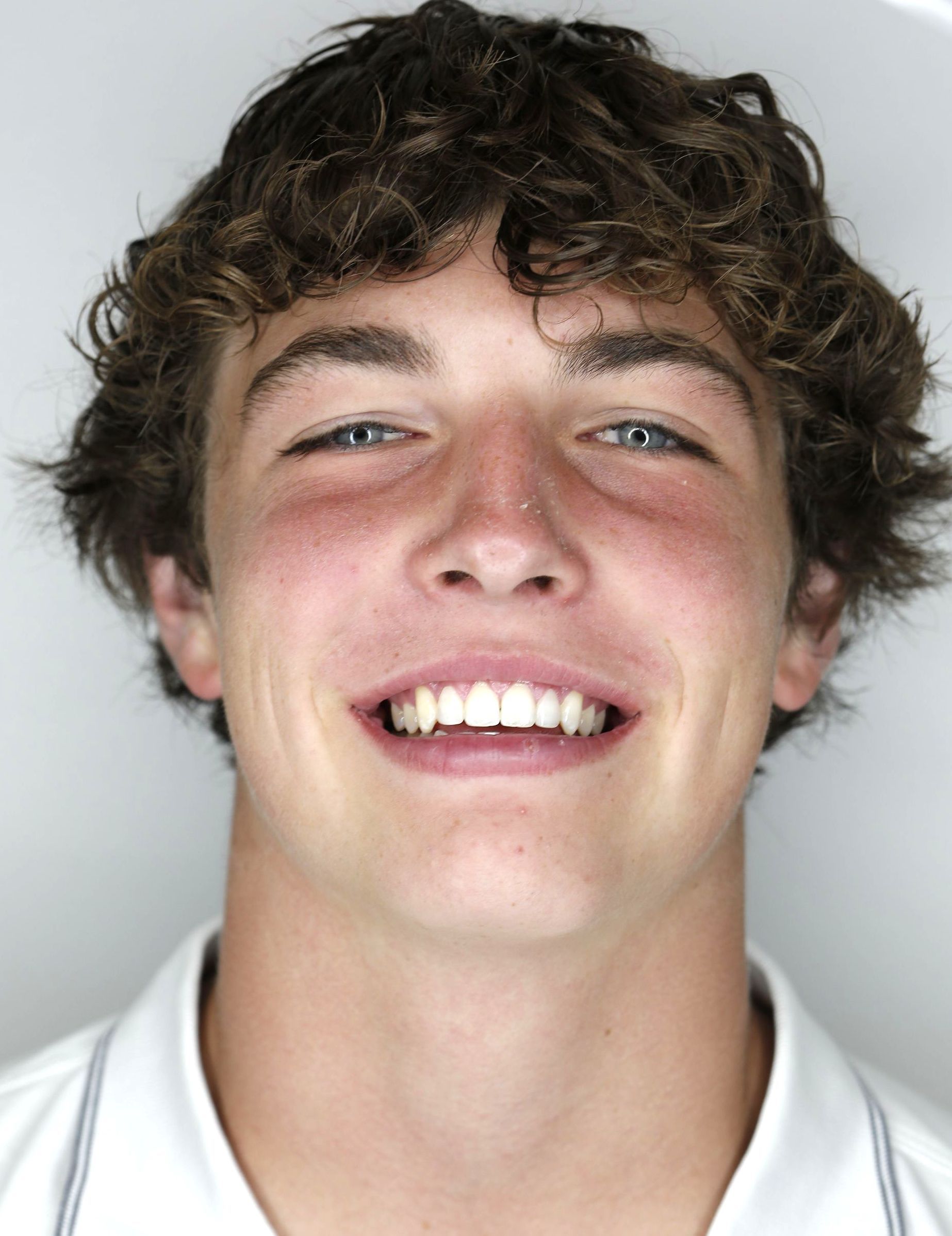 A young man with curly hair is smiling for the camera