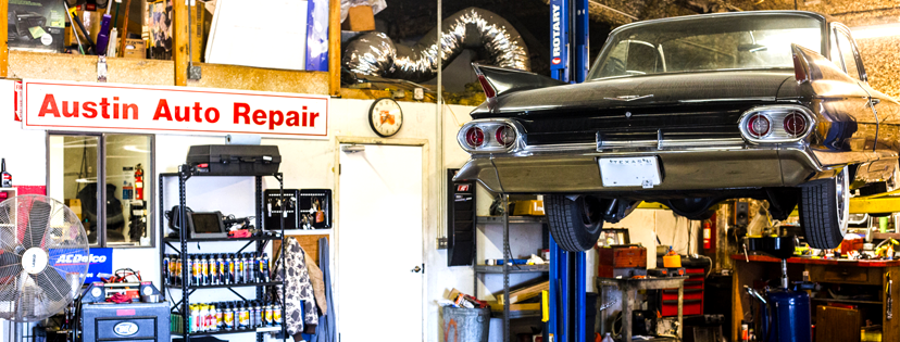 A car is sitting on a lift in a garage under a sign that says austin auto repair.