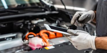 A mechanic is using a tablet computer while working on a car.