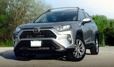 Silver Toyota SUV parked on a road, front view with trees in the background.