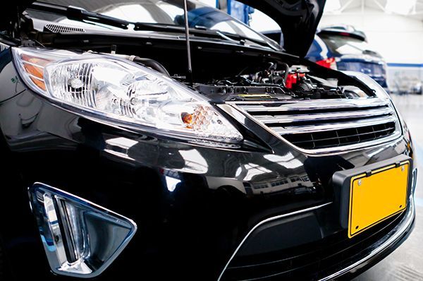 A black car with the hood open in a garage.