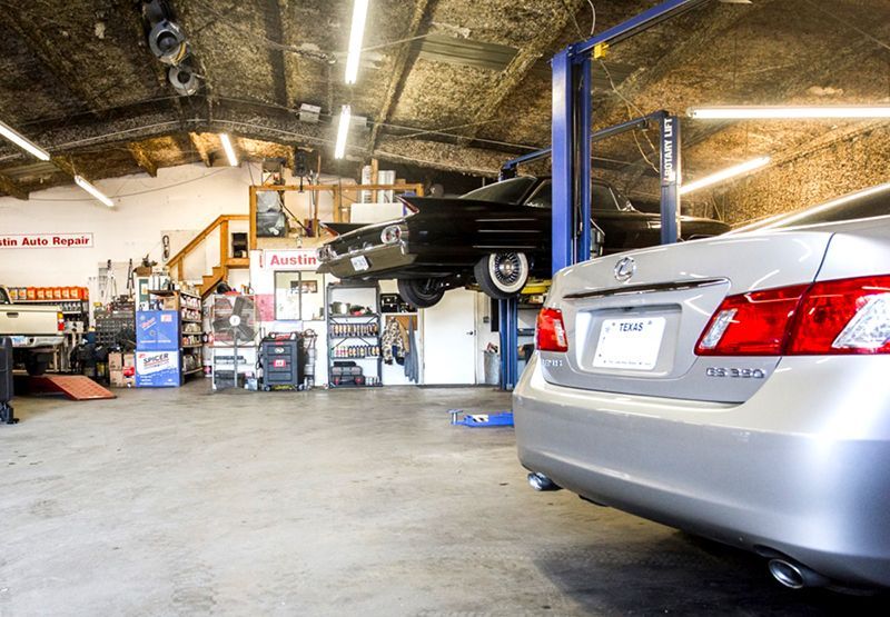 Two cars are sitting on a lift in a garage.