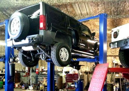 A hummer is on a lift in a garage