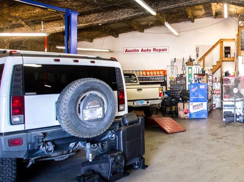 A white hummer is sitting on a lift in a garage.