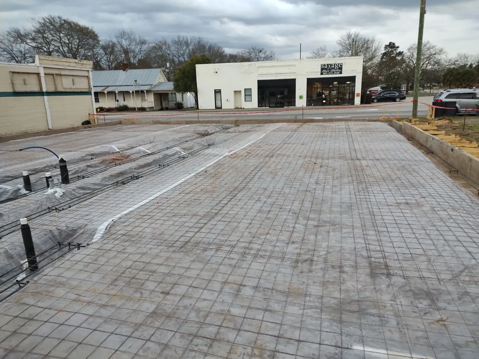 Empty paved parking lot with a white building and overcast sky in the background
