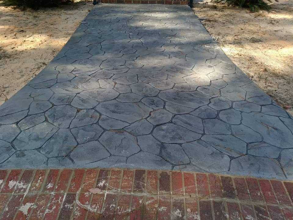 Brick walkway leading to a cracked gray stone path in a sunny outdoor area