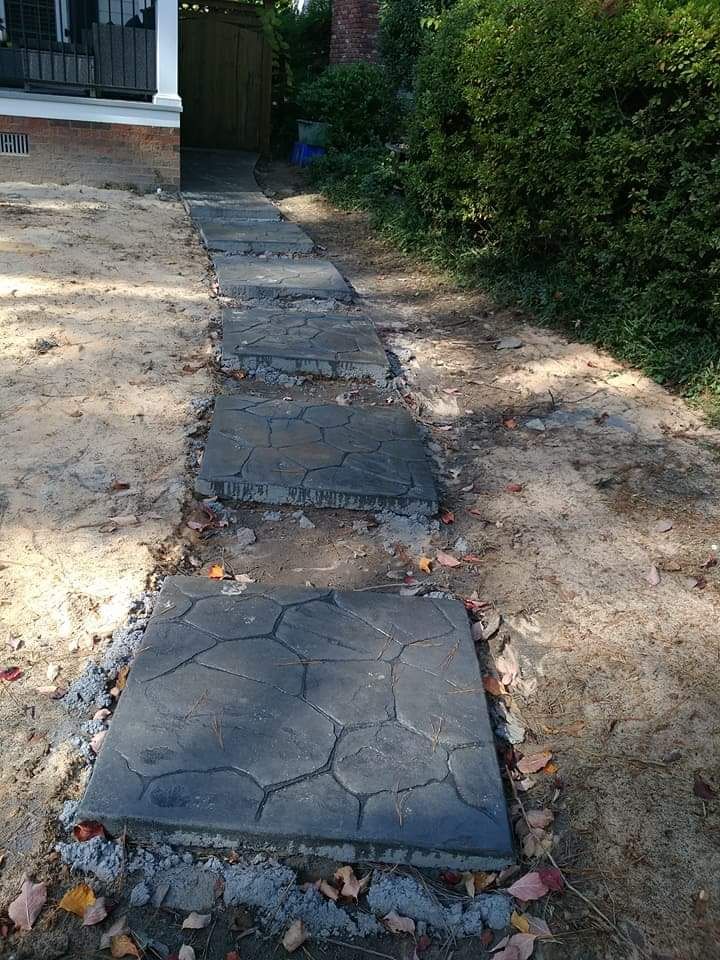 Cracked concrete stepping-stone path leading from a house into a shaded yard