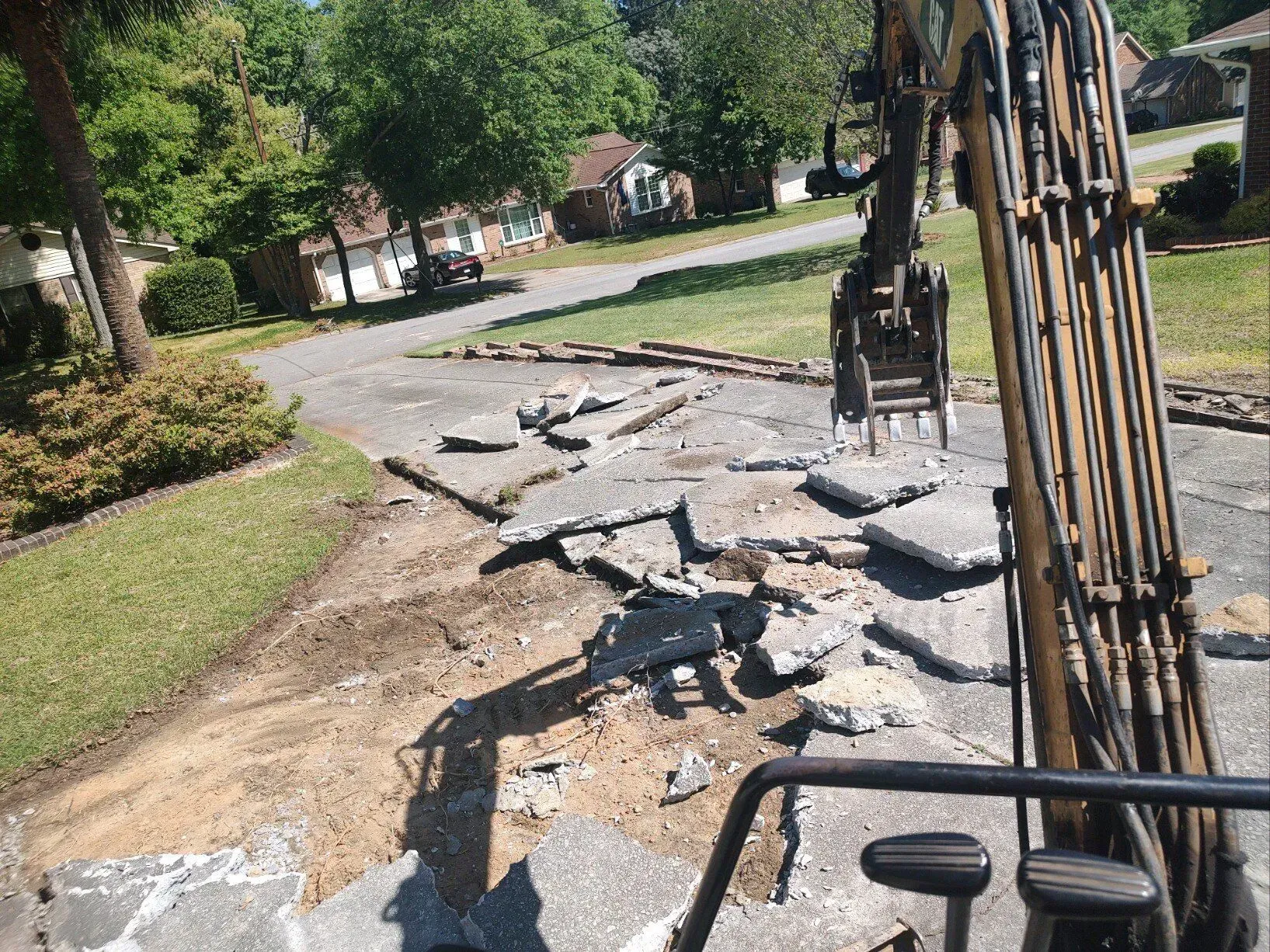 Roadside debris and a damaged fence post along a suburban street, with trees and houses nearby