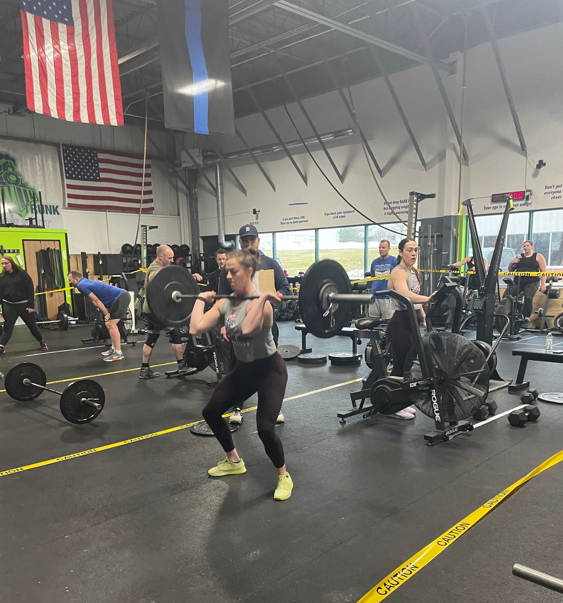 People exercising in Grand Trunk CrossFit, a gym in New Hudson, MI with barbells and American flags on the wall