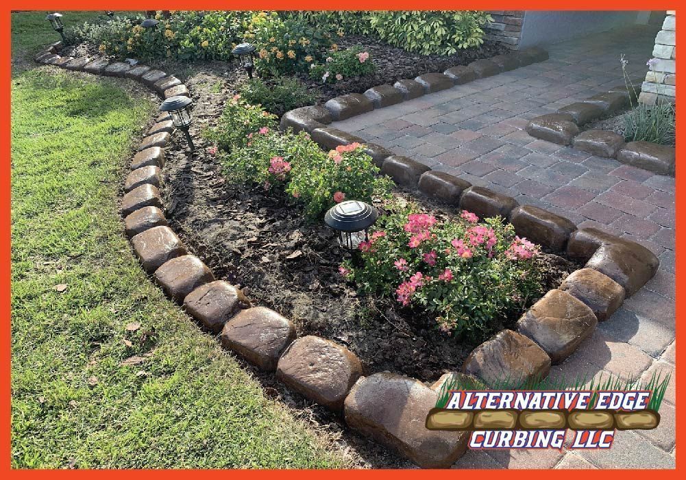 Landscape bed with decorative curb, flowers, and walkway. Brown edging, green grass.