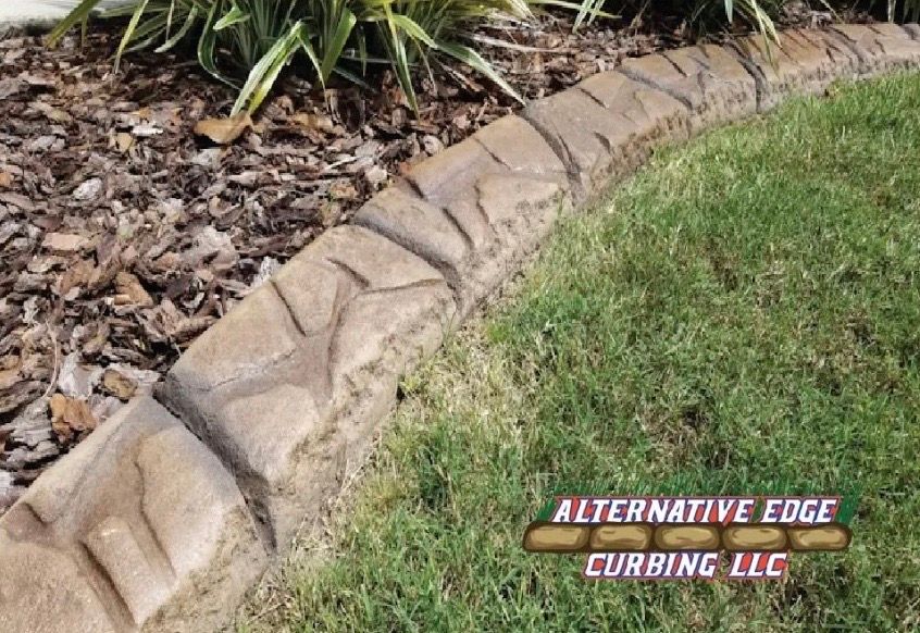Curved concrete curbing with a textured design separates grass from mulch and plants.