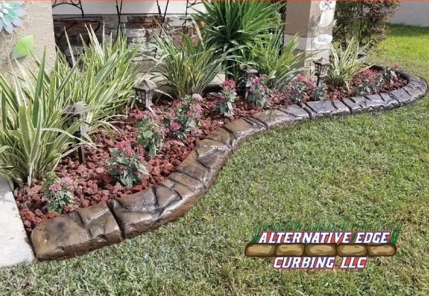 Lawn with decorative concrete curbing, red mulch, plants, and grass. 