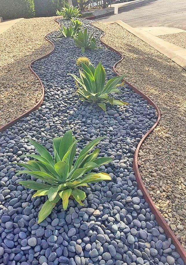 Narrow garden bed with agave plants, black pebbles, edged by red and tan gravel.