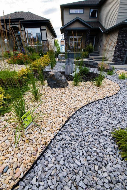 Landscaped front yard with gray and tan gravel paths, plants, and a large rock.