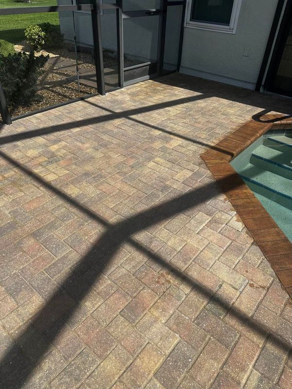 Brick paver patio with pool, shaded by screen enclosure.