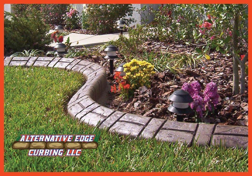 Curved concrete curbing edging a flower bed, with grass, plants, and garden lights.