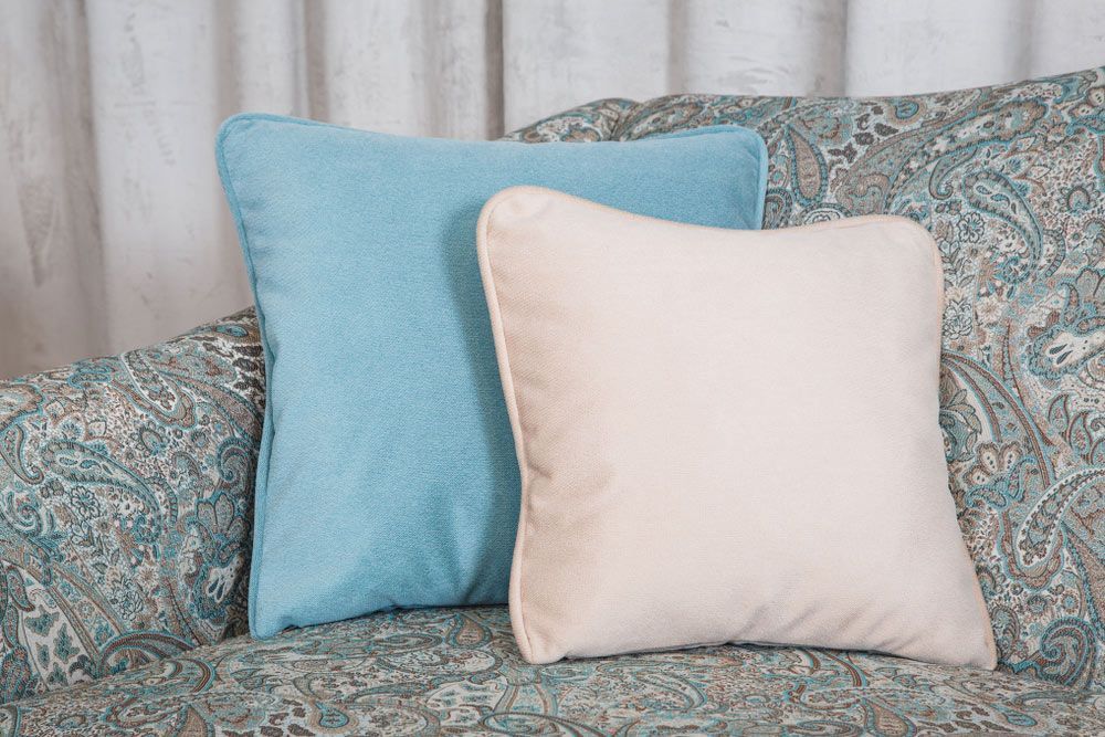 Two Pillows, One Blue And One White, Are Sitting On A Couch — Coastal Upholstery In Berkeley Vale, NSW