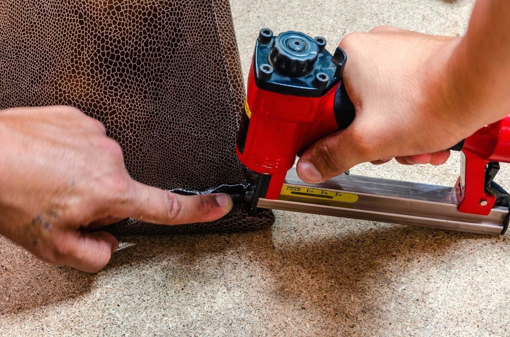 A Person Is Using An Air Stapler To Staple A Piece Of Fabric — Coastal Upholstery In Berkeley Vale, NSW