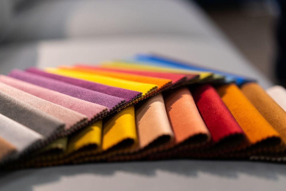 A Bunch Of Different Colored Fabrics Are Stacked On Top Of Each Other On A Table — Coastal Upholstery In Berkeley Vale, NSW