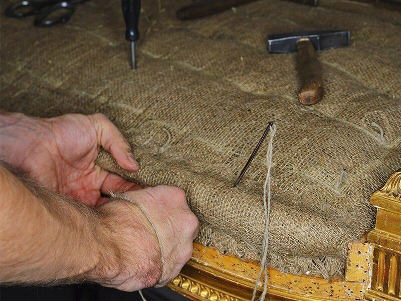 A Person Is Working On A Piece Of Furniture With A Hammer — Coastal Upholstery In Berkeley Vale, NSW