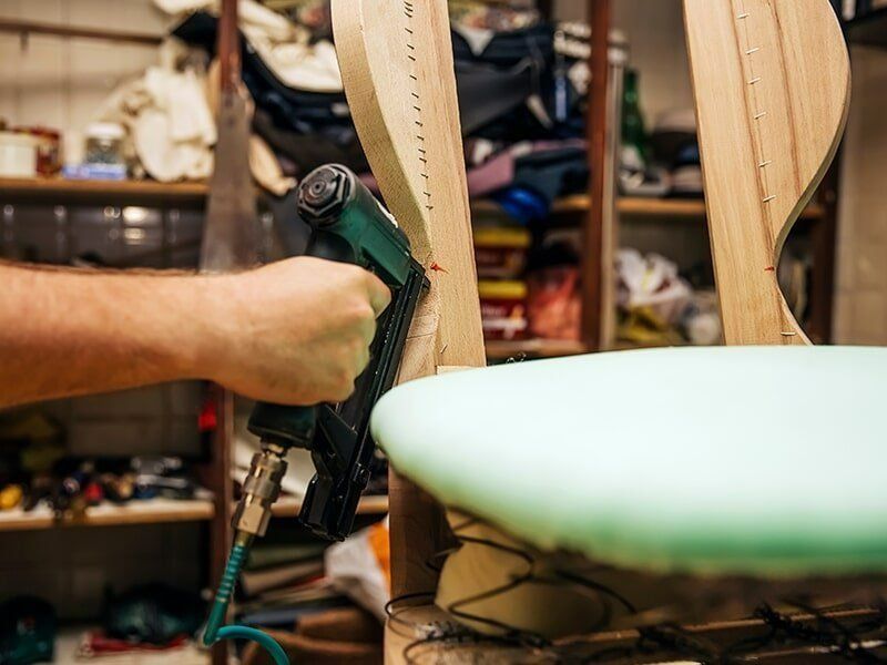 A Person Is Using A Stapler To Fix A Chair Cushion — Coastal Upholstery In Berkeley Vale, NSW