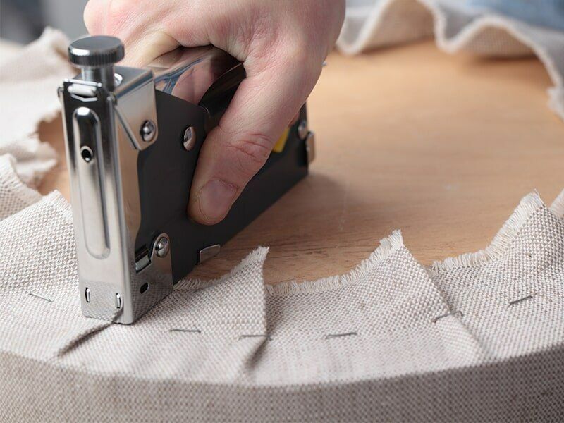 A Person Is Using A Stapler To Staple A Piece Of Fabric — Coastal Upholstery In Berkeley Vale, NSW
