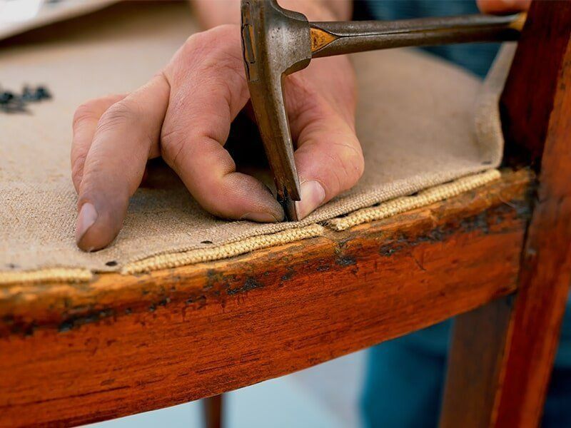 A Person Is Using A Hammer To Fix A Chair — Coastal Upholstery In Berkeley Vale, NSW