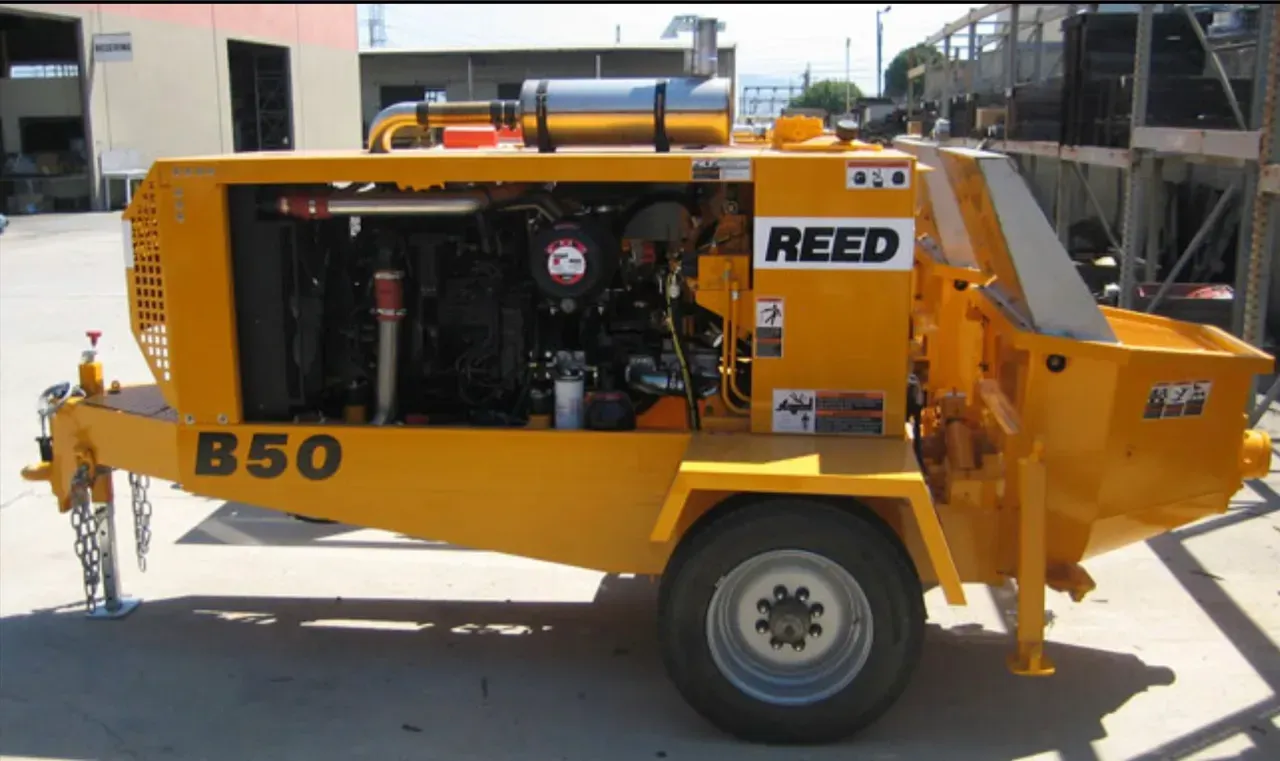 Yellow Reed B50 concrete pump on a trailer, parked outdoors.