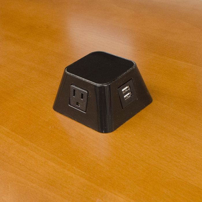 A black cube with two outlets on top of a wooden table