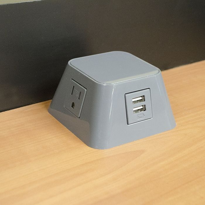 A gray electrical outlet with two usb ports on a wooden table