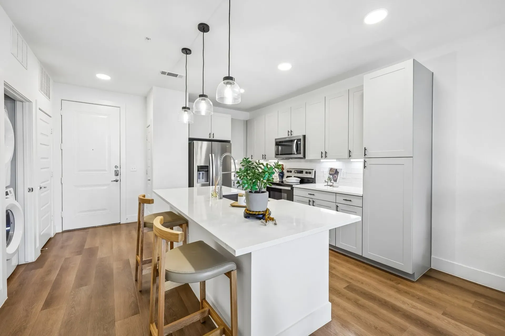 Modern kitchen with white island, pendant lights, and stainless steel appliances at The Grayson.