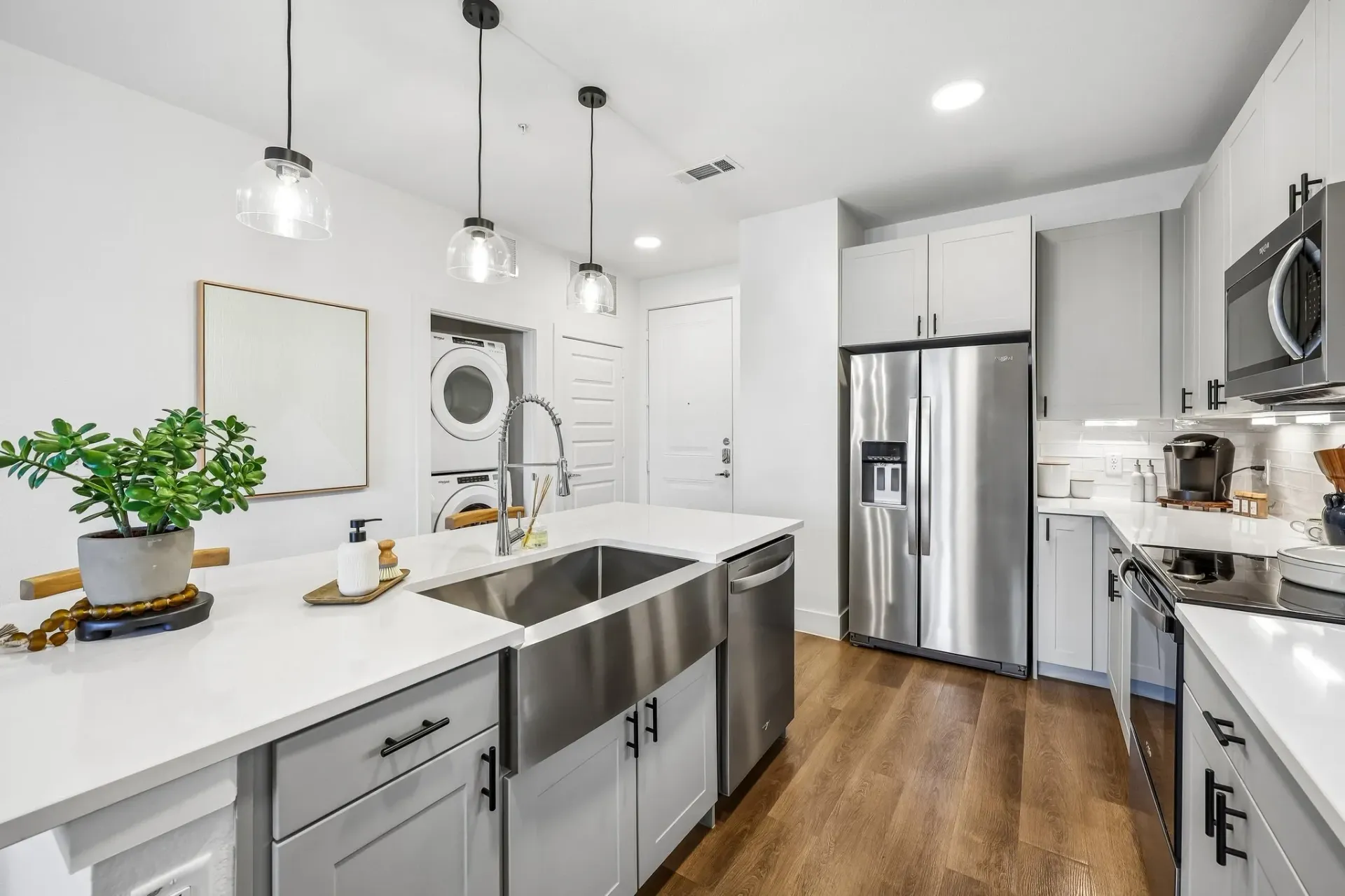 Bright modern kitchen with white cabinets, stainless appliances, island, and wood floors