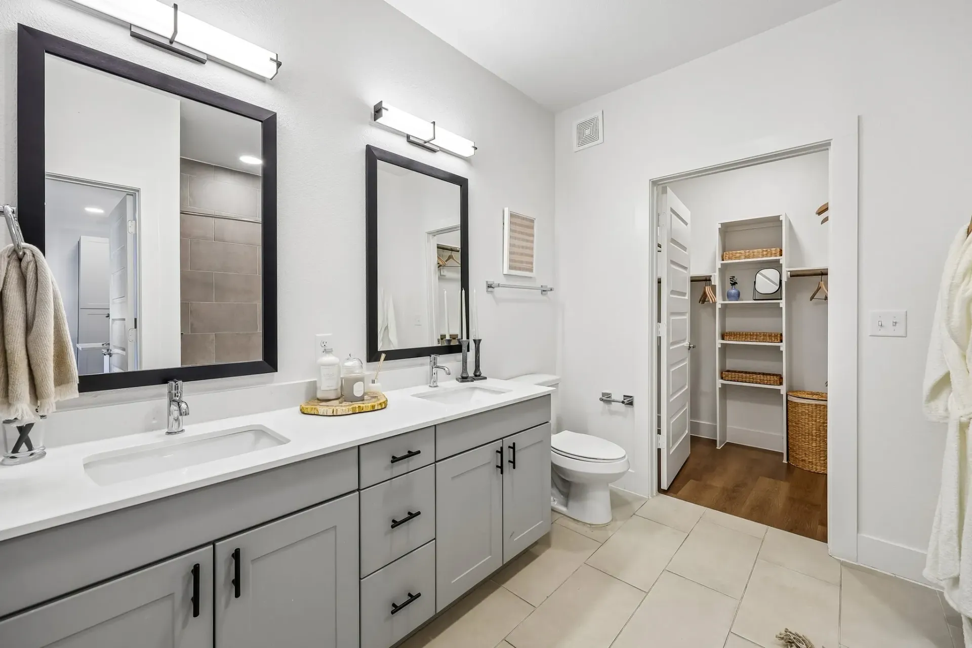 Modern bathroom with double vanity, large mirrors, and walk-in closet at The Grayson.