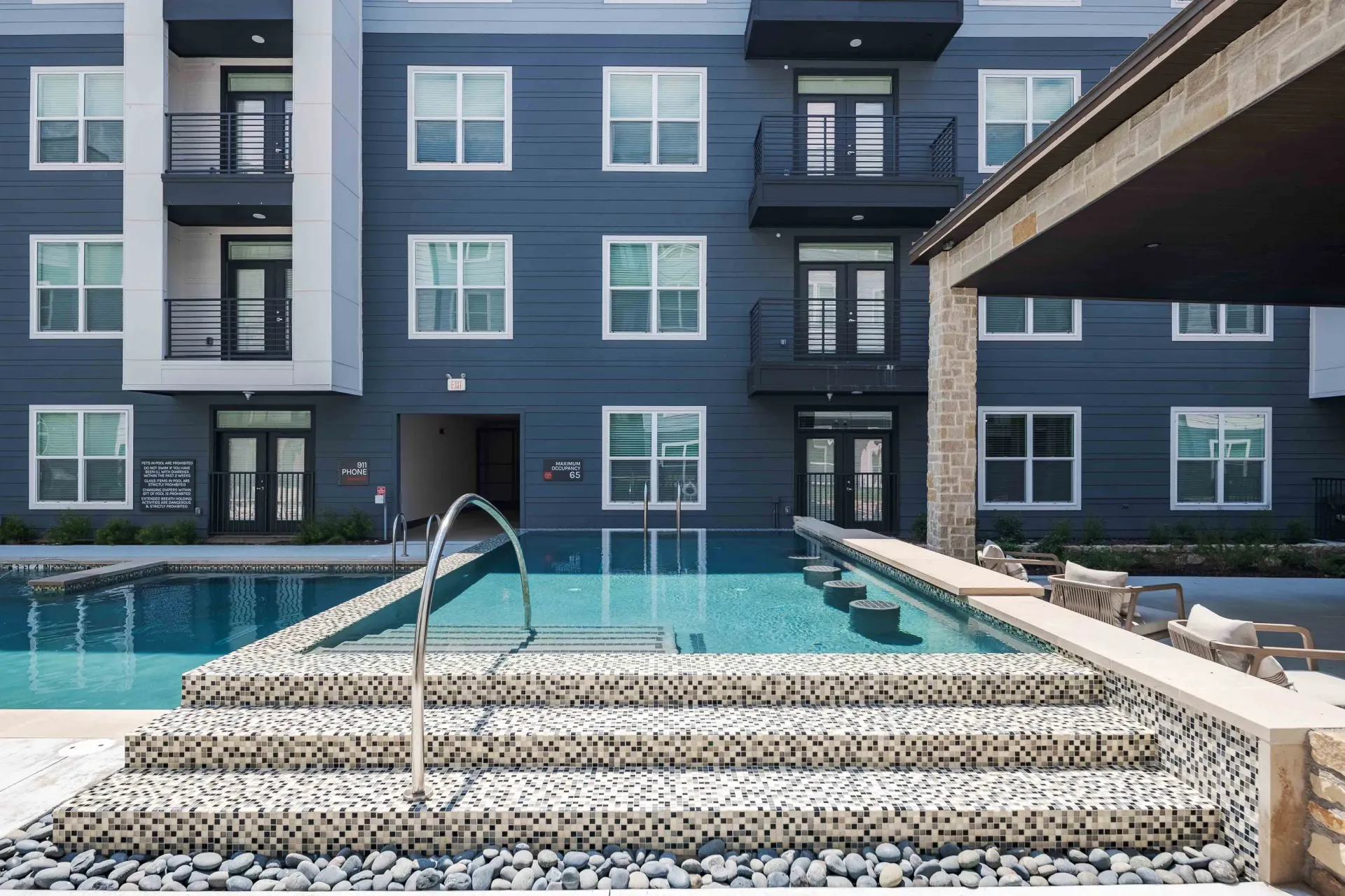 A modern apartment building with a resort-style pool and lounge seating at The Grayson in Fort Worth, TX.